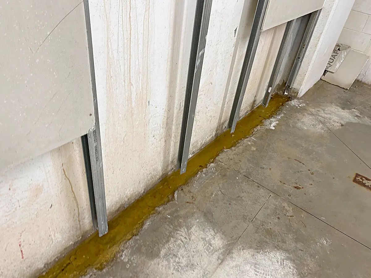 Acqua e macchie alla base del muro dietro la controparete aperta