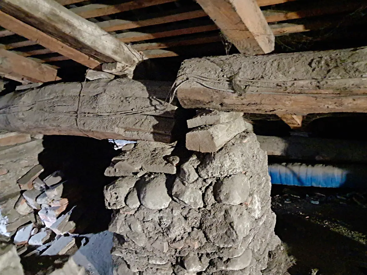 Appoggio di due travi su un pilastro in ciottoli, con spessori in legno e legature in filo di ferro
