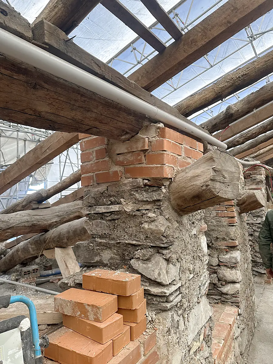 Testa di muro ricostruita in mattoni pieni sotto una trave in legno